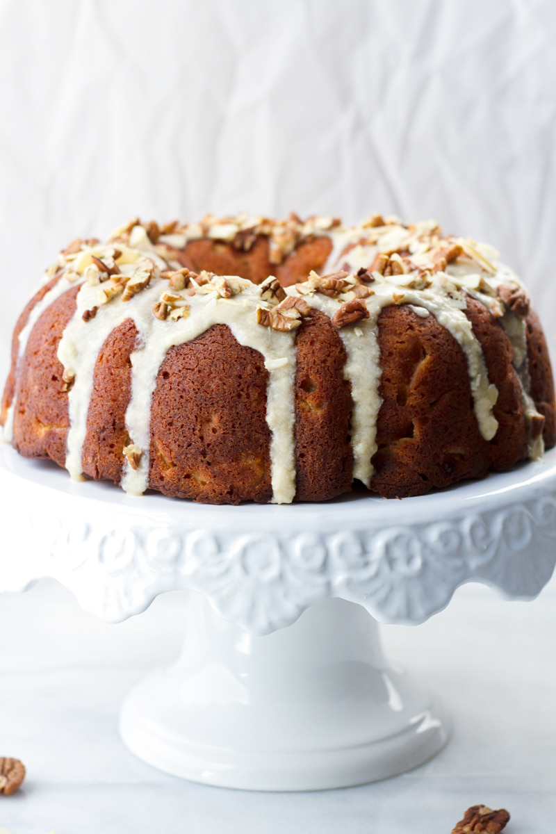 fresh apple bundt cake with glaze on cake stand