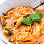 Bowl of Creamy Tortellini Soup with Fresh Spinach Leaves