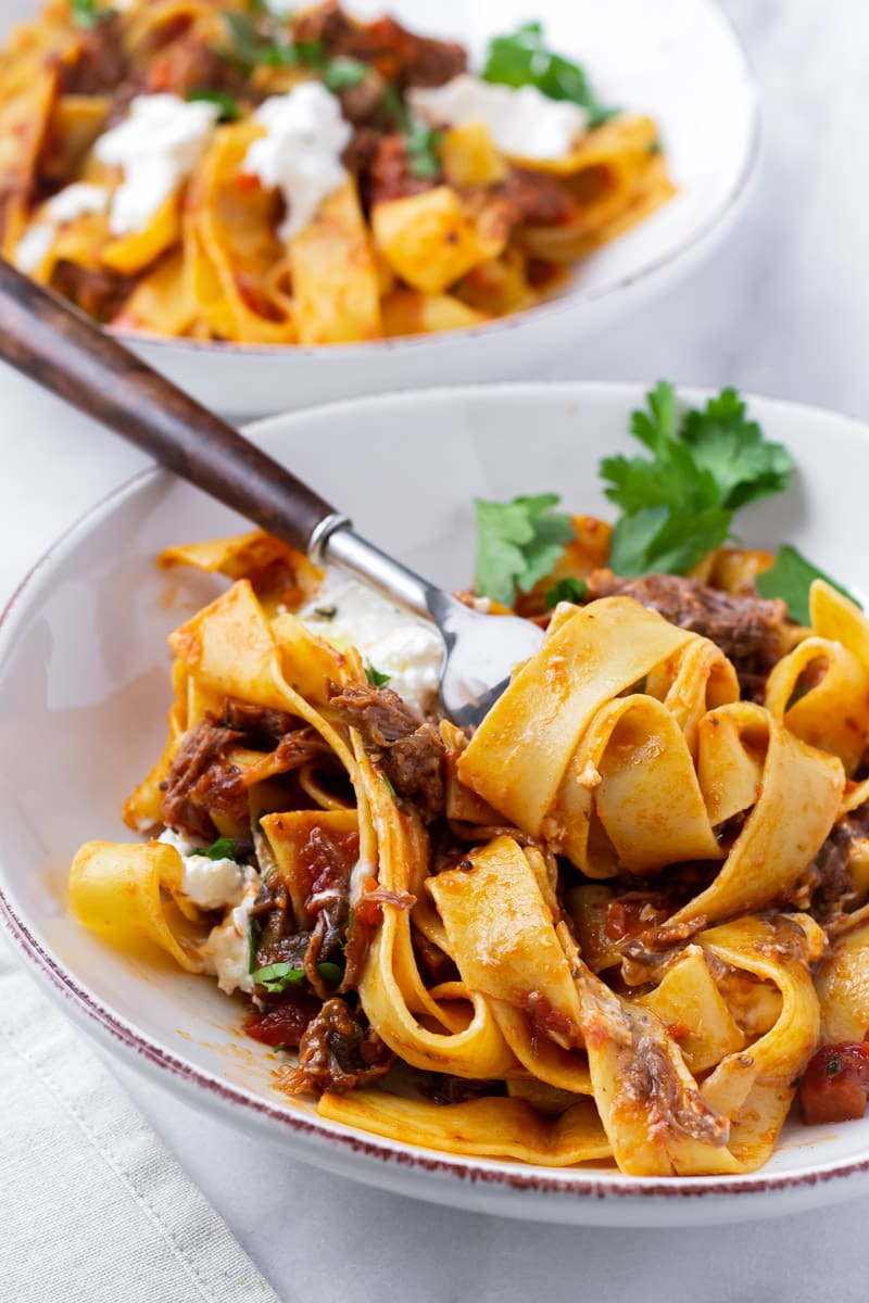 Fork twisting pappardelle pasta with ragu sauce