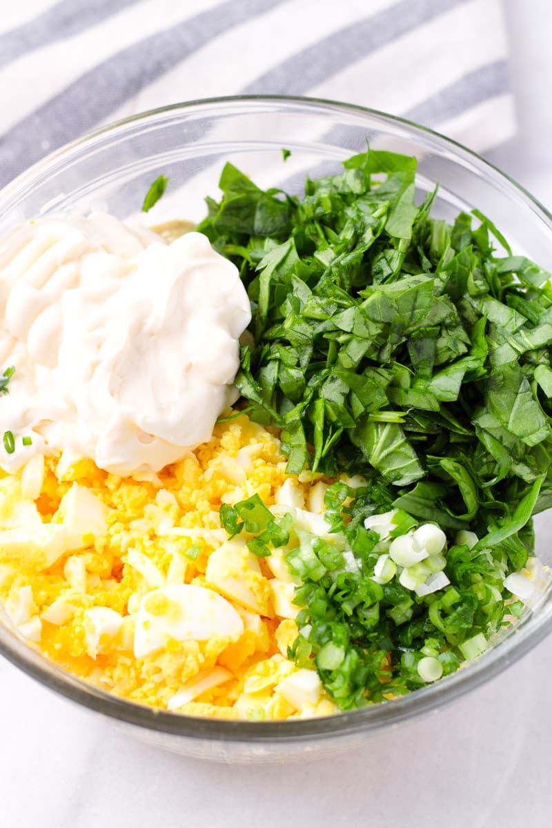 Bowl of chopped eggs, mayonnaise, spinach, scallions, and seasoning