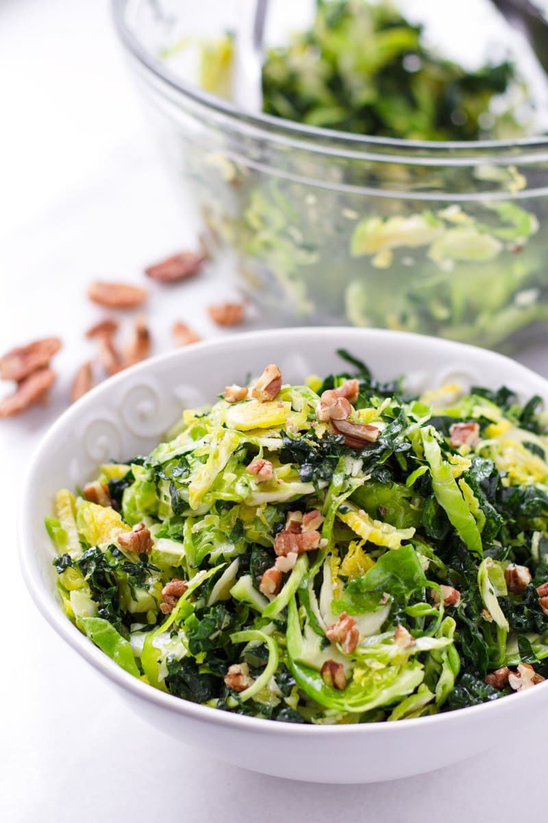 Bowl of brussels sprouts and kale salad with chopped pecans