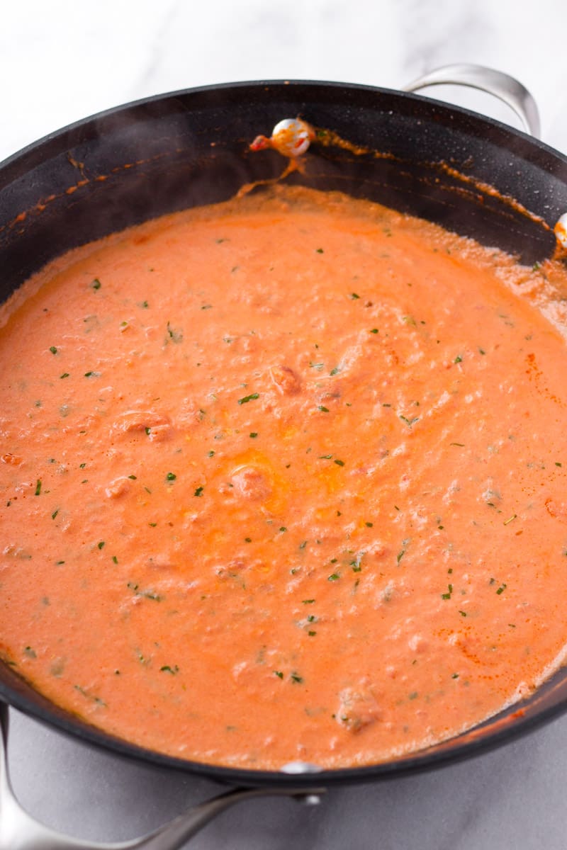 Creamy tomato sauce with basil on a black non stick skillet