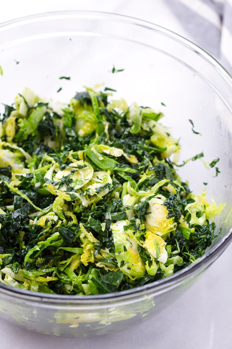 Bowl of raw and sliced lacinato kale and ingredients for salad