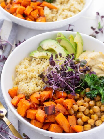 Bowl of sweet potato quinoa bowl with chickpeas, avocado, kale, and hummus