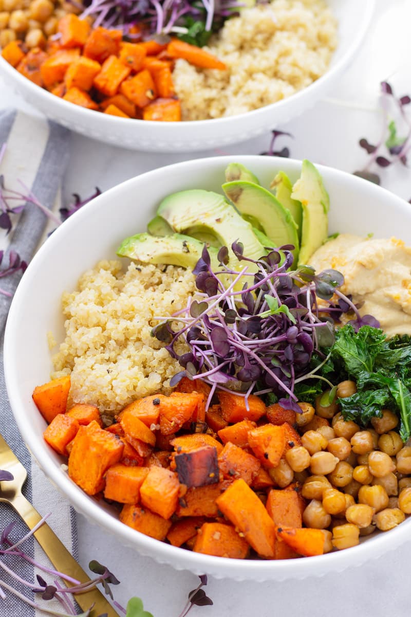 Bowl of sweet potato quinoa bowl with chickpeas, avocado, kale, and hummus