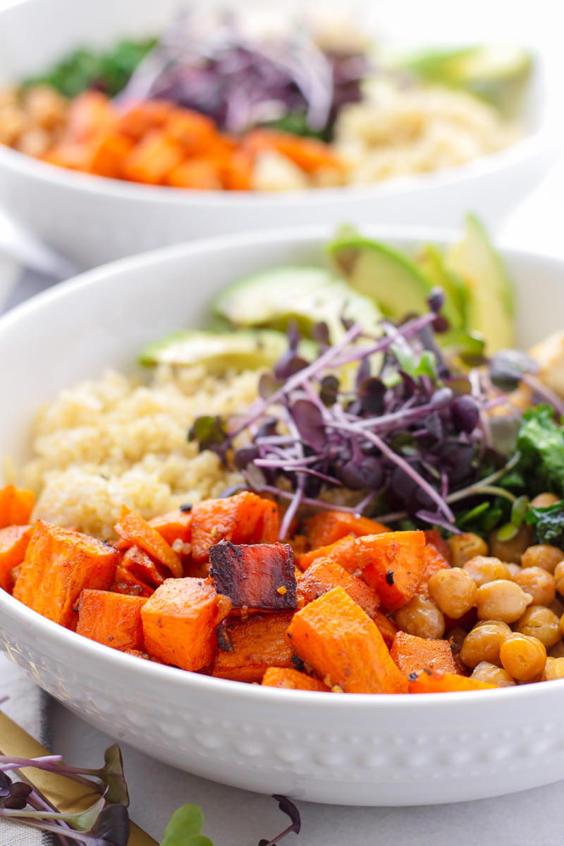 Close up of sweet potato, chickpeas, and quinoa grain bowl with purple micro greens