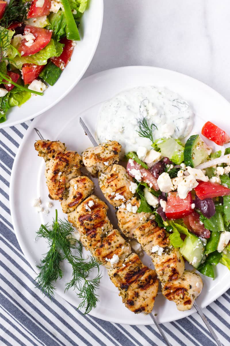 white platter of grilled chicken kabobs on a blue and white striped napkin