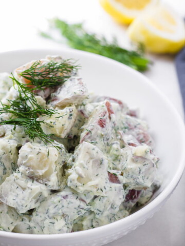 Red potatoes with yogurt and dill dressing in a round bowl