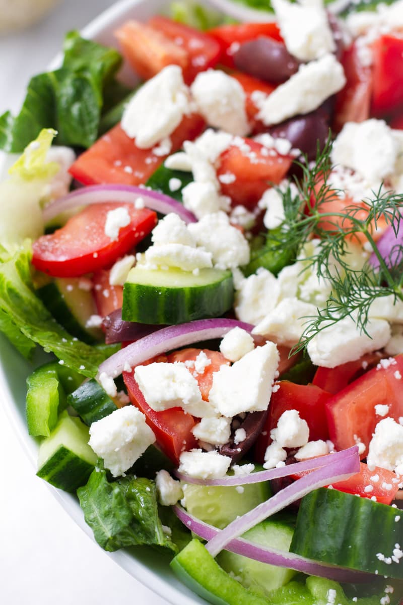 close up of salad with cucumbers, tomatoes, red onions, green bell peppers and crumbled feta