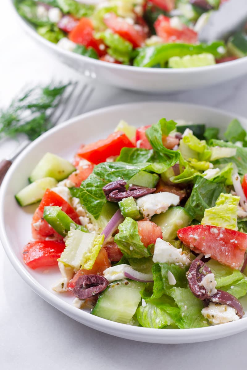 Side portion of Greek style salad on a shallow white plate