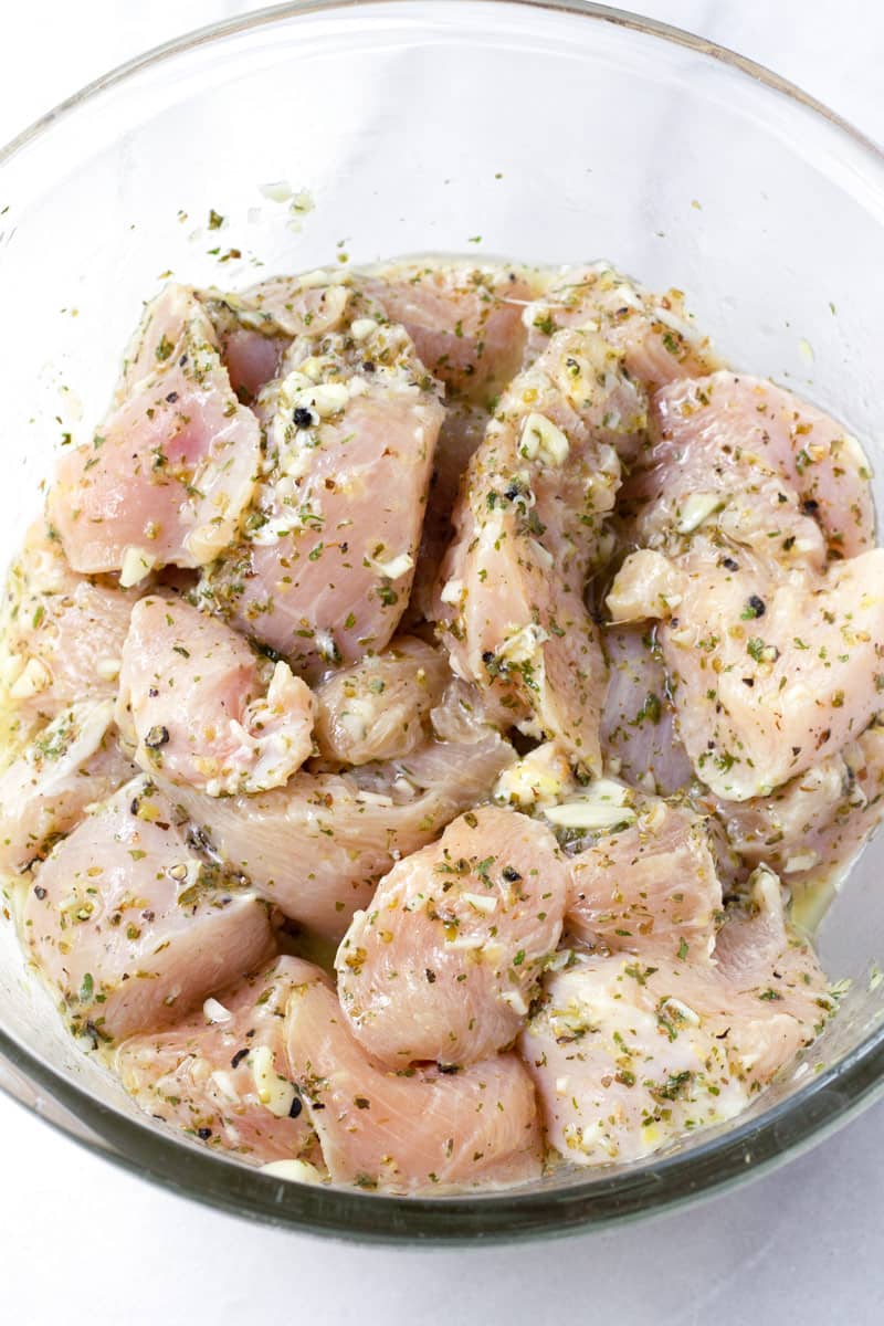 Glass bowl with cubed chicken breast in lemon and oregano marinade