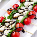 Close up of tomato, mozzarella, and basil skewers drizzled with balsamic