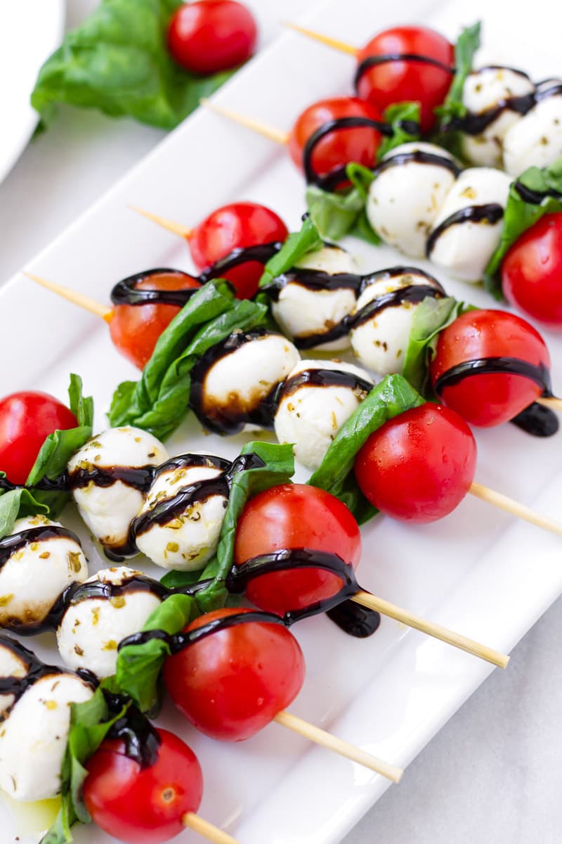 Close up of tomato, mozzarella, and basil skewers drizzled with balsamic