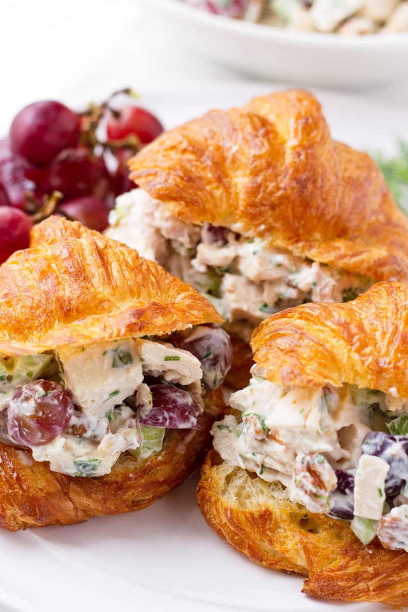 Three croissant sandwiches with creamy chicken salad and grapes