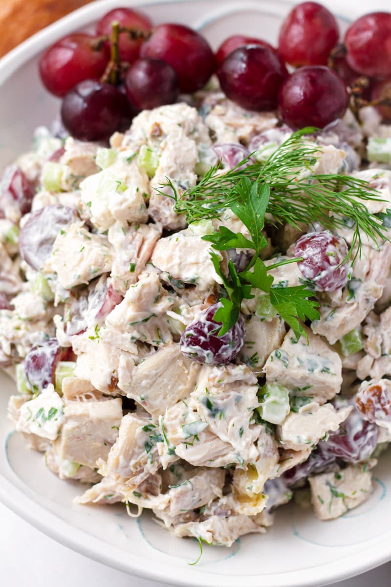 Close up of grape chicken salad with dill and parsley garnish