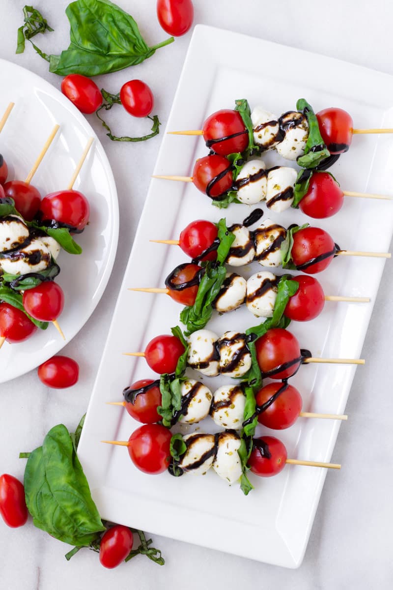 Top view of skewered caprese ingredients arranged on a white platter
