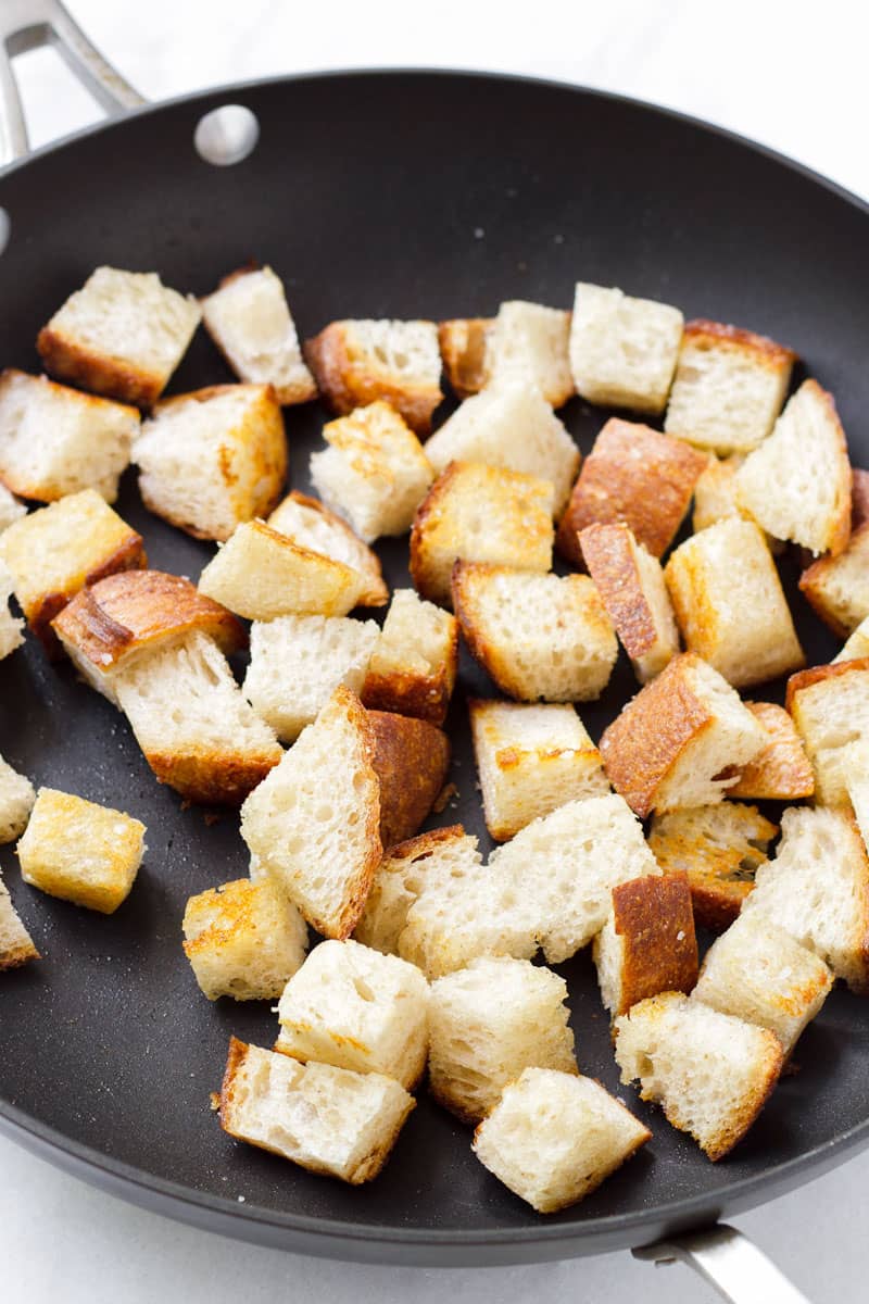 Large dark skillet with toasted bread cubes and olive oil