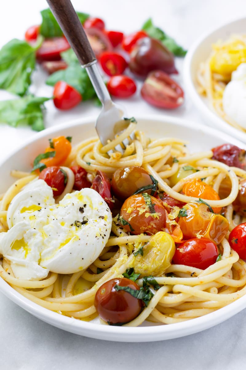Plate with fresh tomato sauce and spaghetti and burrata and a wooden fork