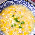 close up of bowl with corn soup and green onion garnish