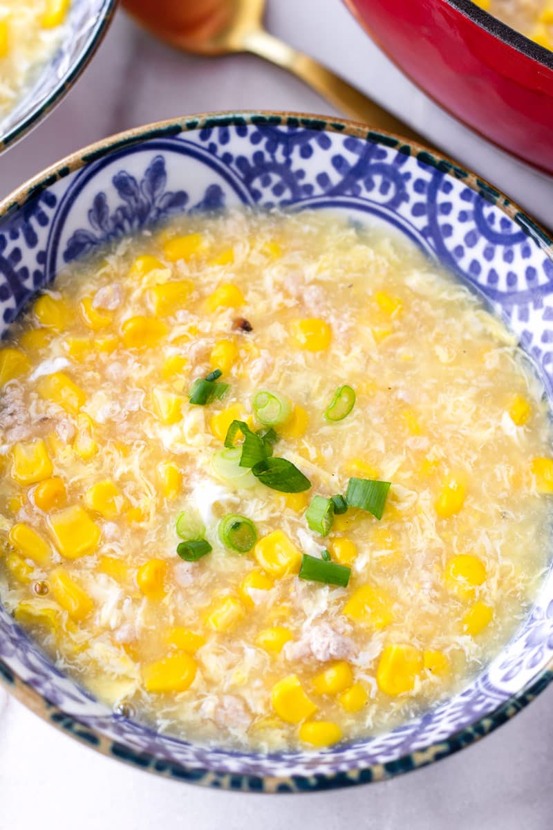 close up of bowl with corn soup and green onion garnish