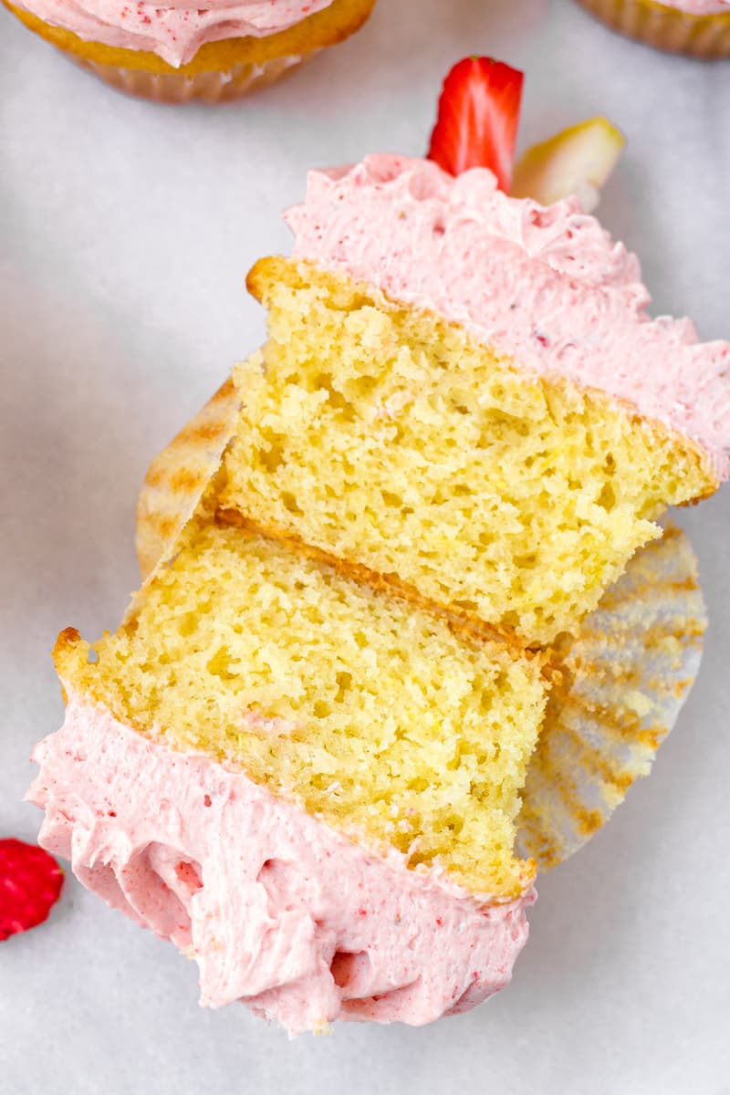 The inside of a lemon yellow cupcake with pink frosting