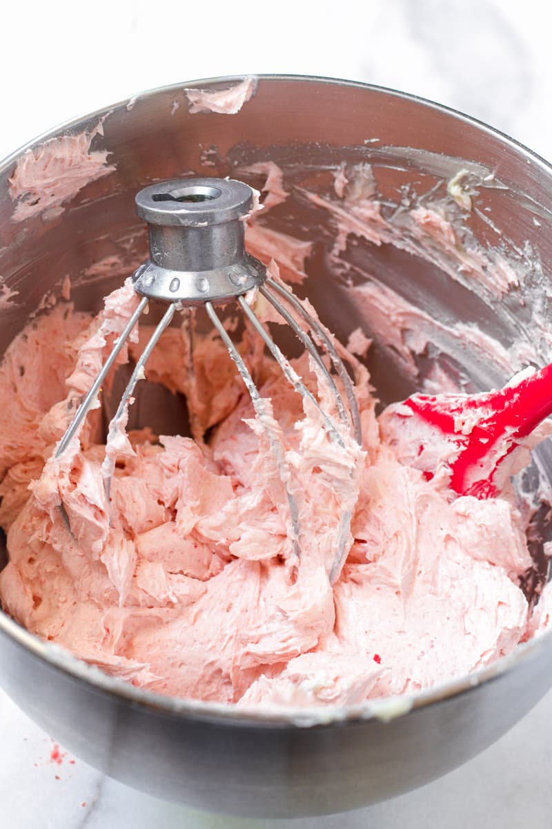 Strawberry buttercream frosting with a red mixing spoon