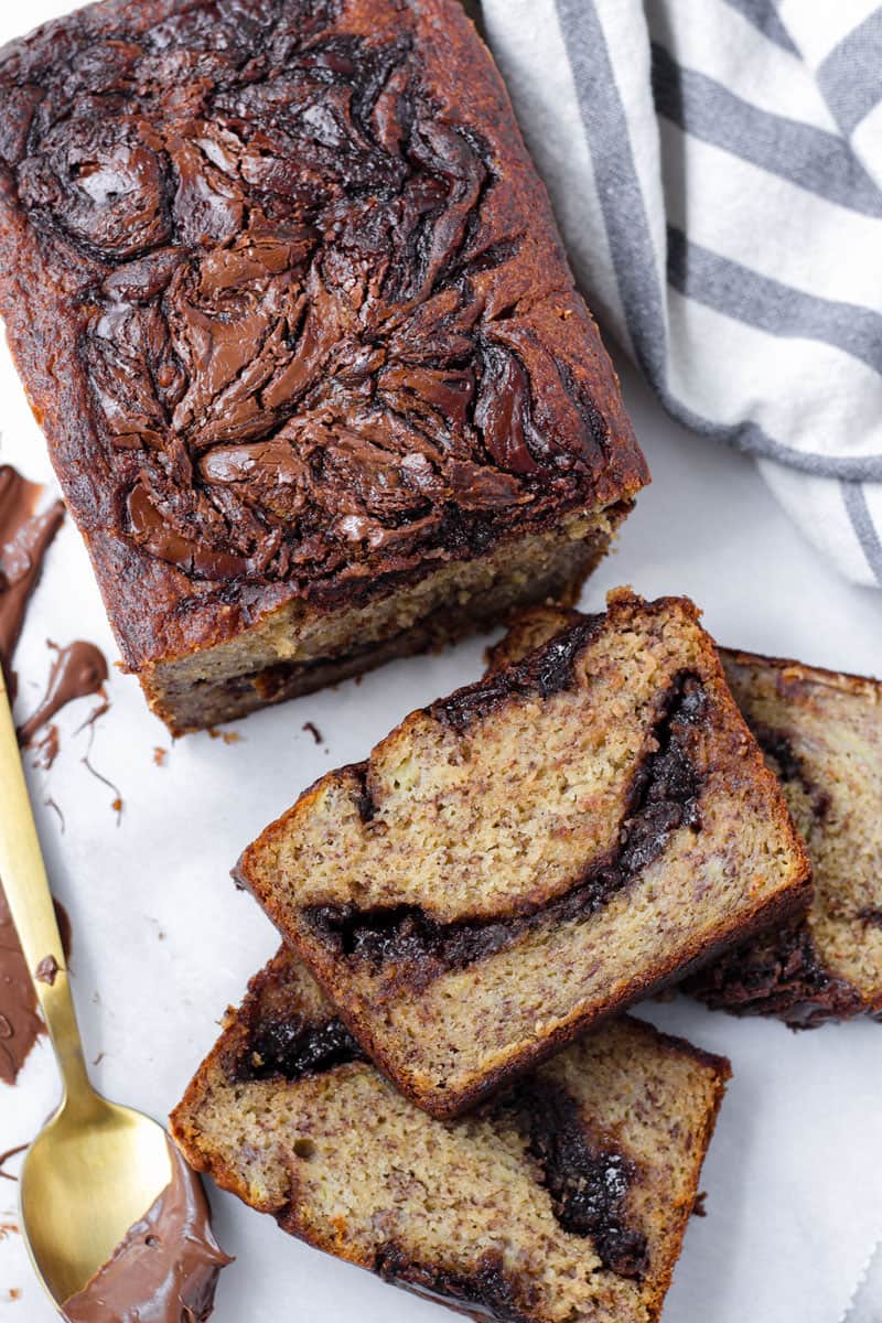 top view hazelnut chocolate banana bread with striped towel and golden spoon