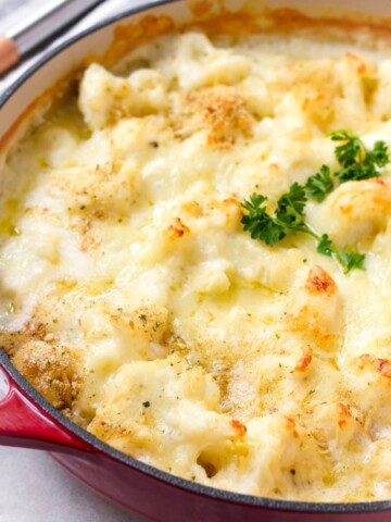 baked and golden brown cauliflower with cheese in a red Dutch oven pot