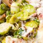 Close up of cheese baked brussels sprouts being scooped up with a spoon