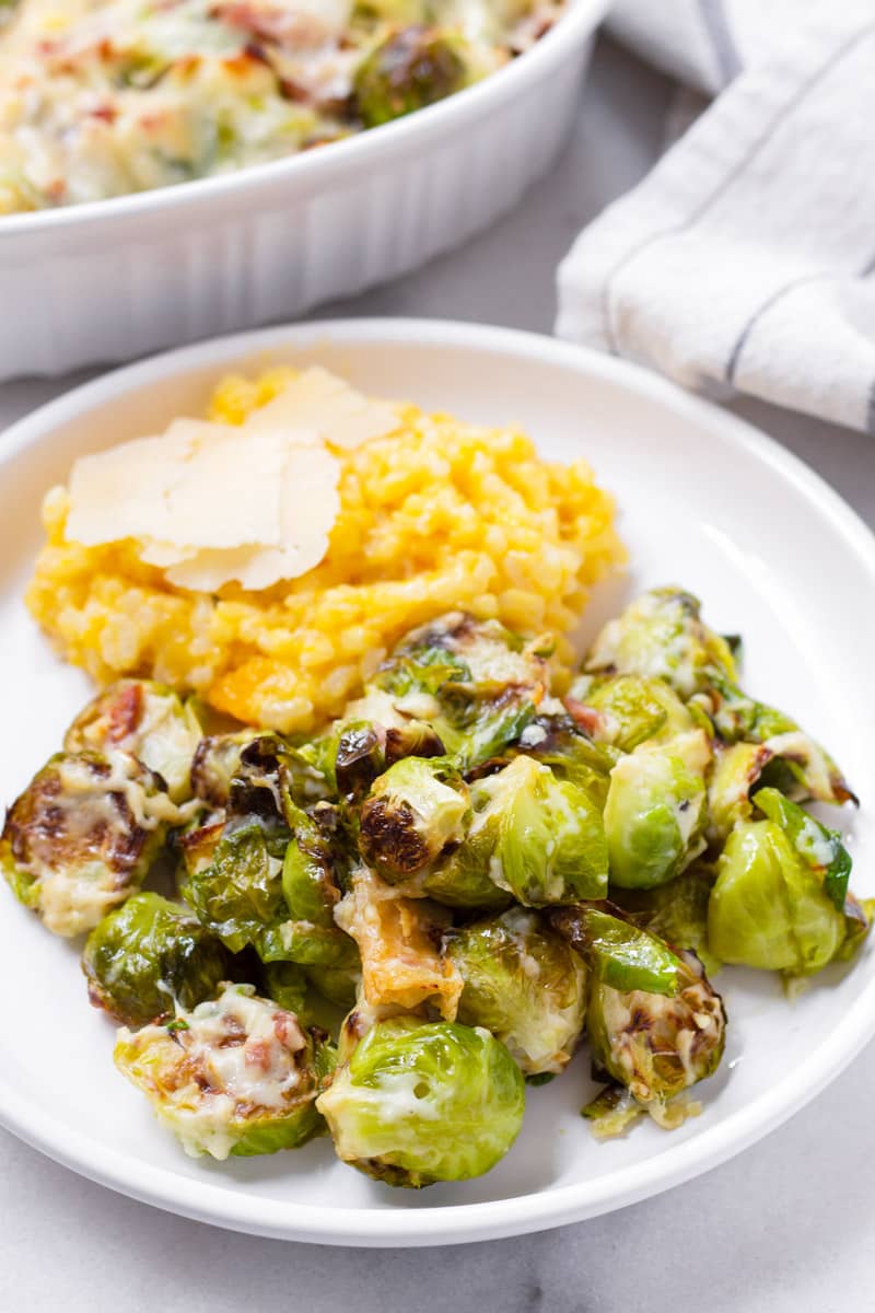 Round plate with a helping of baked brussels sprouts with cheese and a side of risotto