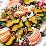 salad platter made of apples, roasted acorn squash, kale, pecans, and pumpkin seeds