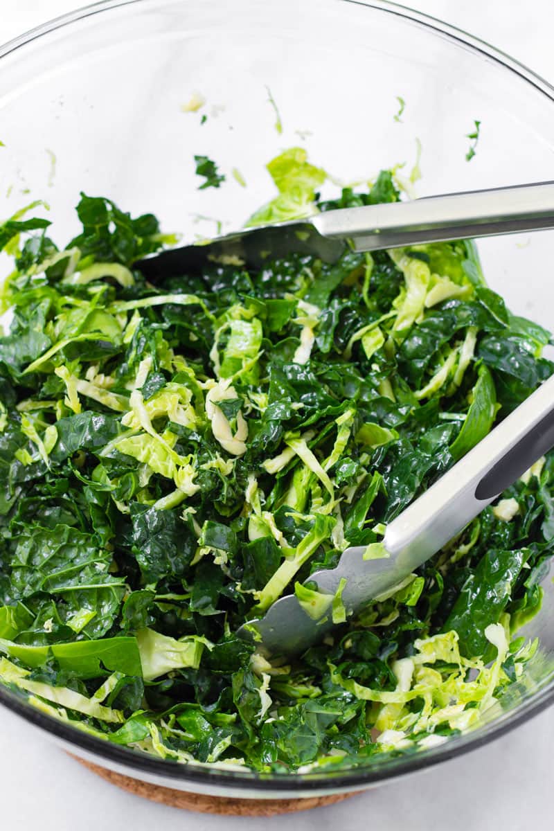 Chopped kale in a bowl and tongs