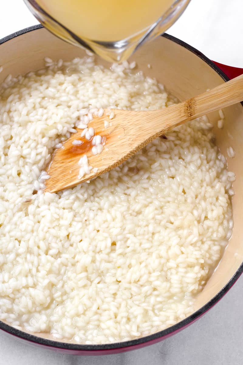 broth being poured into rice and a wooden spoon