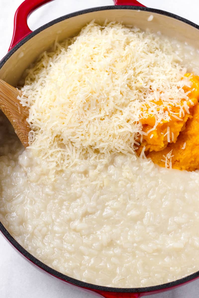 cooked risotto being tossed with grated parmesan cheese and pureed butternut squash