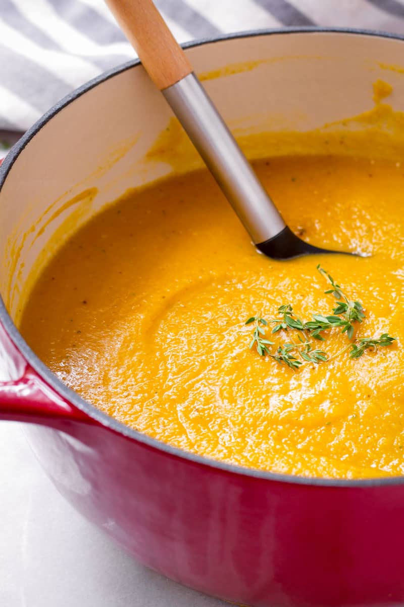 Roasted butternut squash soup in a red pot with a ladle