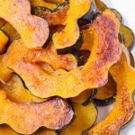 maple acorn squash piled up on top of each other on a round white plate