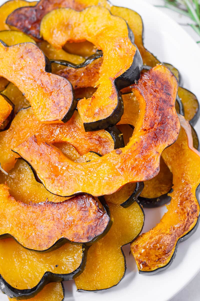 maple acorn squash piled up on top of each other on a round white plate