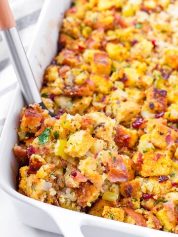 spoon scooping out a serving of cornbread stuffing from a rectangular baking dish