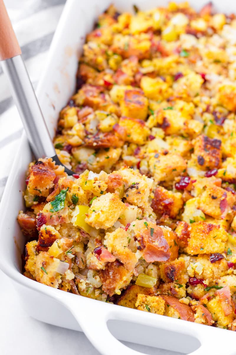 spoon scooping out a serving of cornbread stuffing from a rectangular baking dish