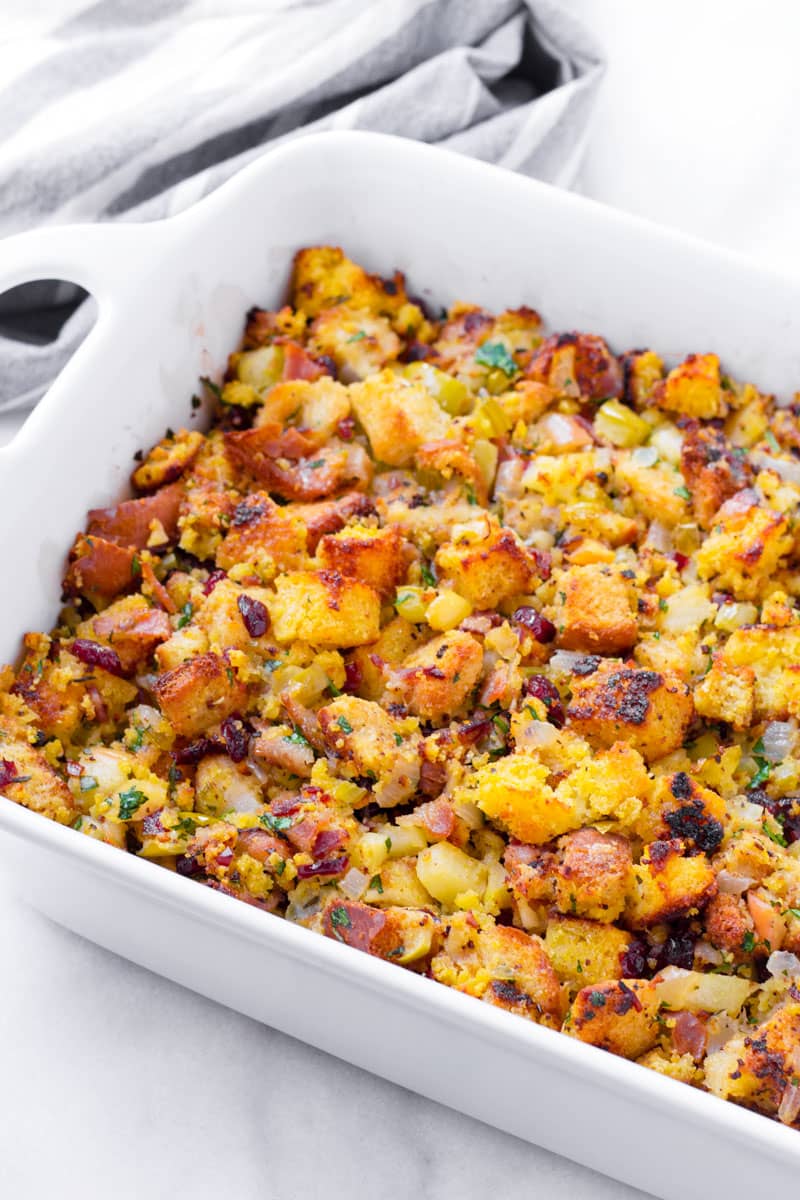 Baked stuffing on a large rectangular baking dish and next to a grey napkin