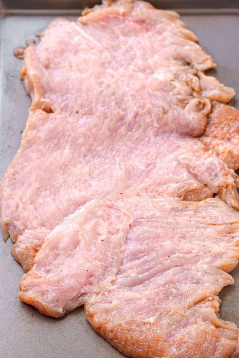 Flattened and butterflied raw turkey breast on sheet pan