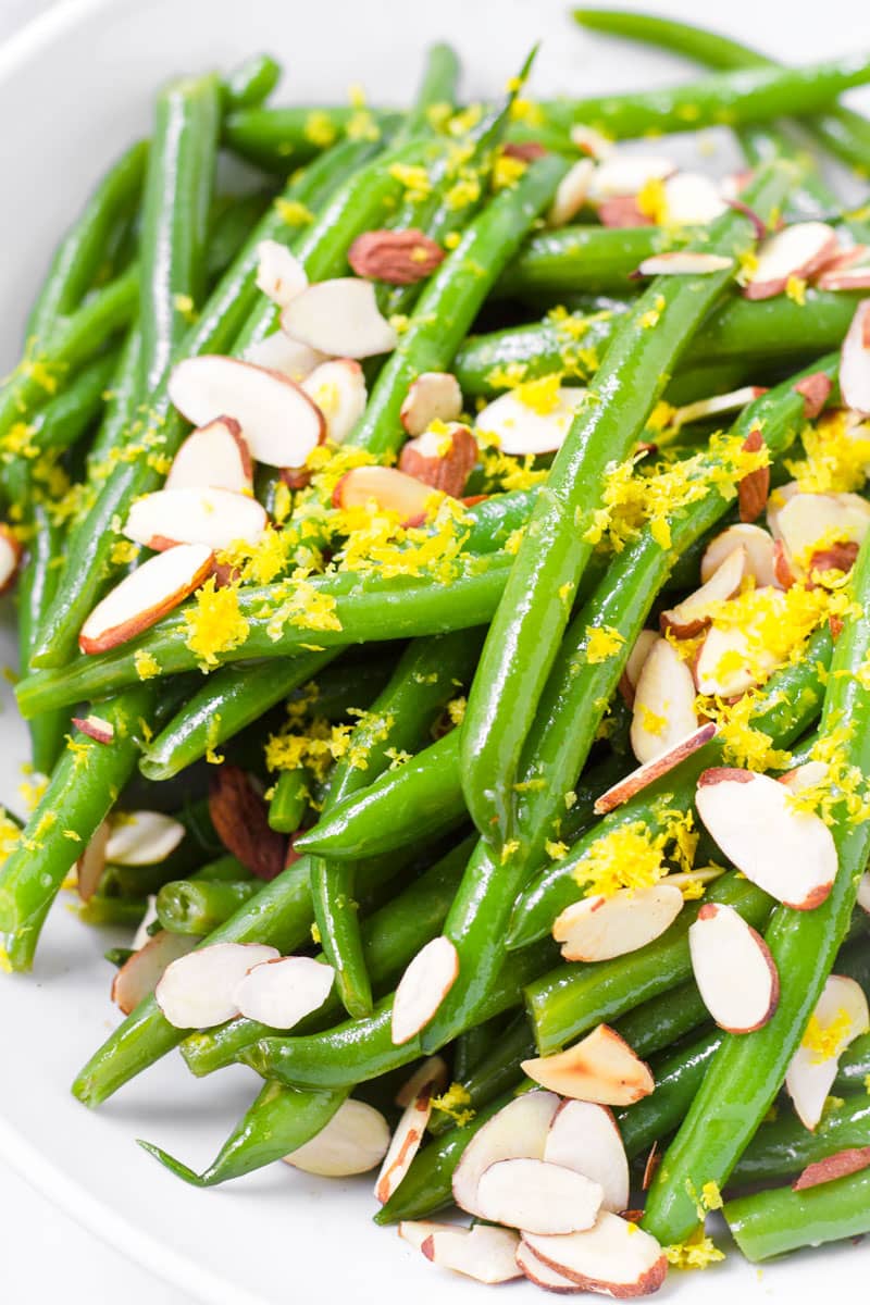 close up of green bean salad tossed with lemon dressing, topped with lemon zest and almonds