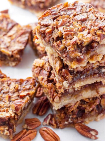 stacked pecan pie bars with a few pecans next to them