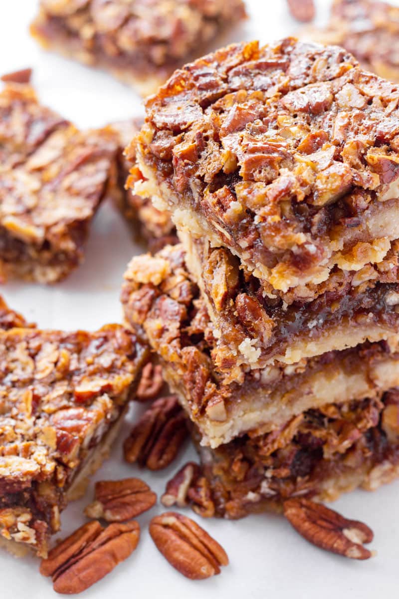 stacked pecan pie bars with a few pecans next to them