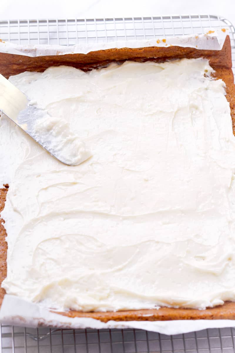 offset spatula spreading cream cheese frosting over cake