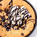 top view of a golden brown skillet cookie with chocolate chunks, ice cream, and fudge