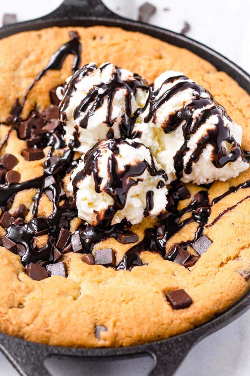 close up of ice cream and chocolate sauce on top of a cookie