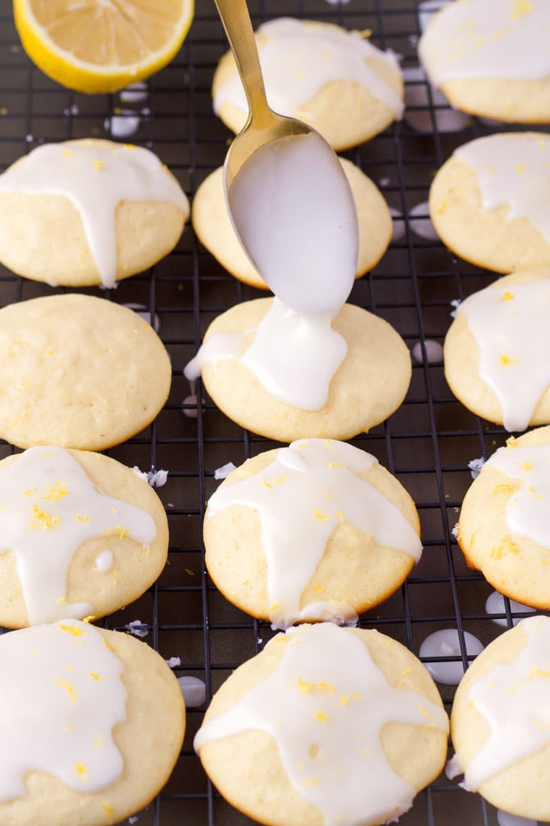 A golden spoon drizzling lemon glaze over cookies