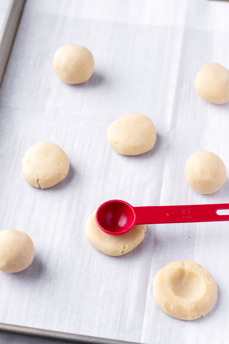 Using a red teaspoon to create an indentation in cookie dough