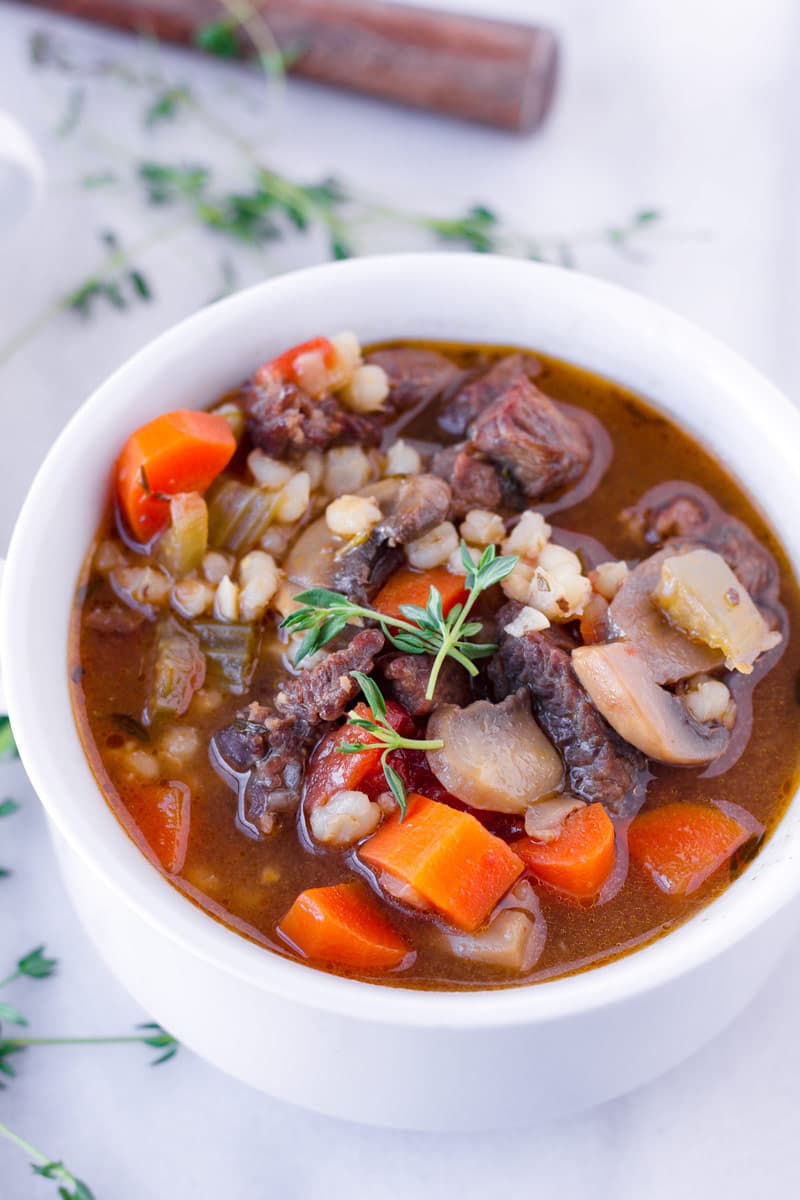 cooked beef and barley soup served in a ceramic bowl